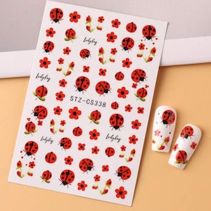 May include: Nail art stickers with red ladybugs and red flowers. The sheet includes the text "Ladybug" and "STZ-CS338". Two nail art samples are also shown with ladybug designs.