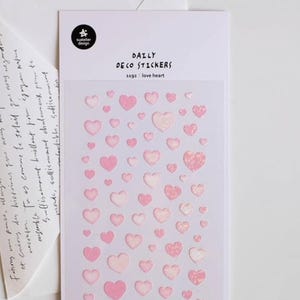May include: A sheet of Daily Deco Stickers with various pink heart designs. The stickers are in different shades of pink and sizes, some with glitter accents. The text "1192: love heart" is printed on the sheet.