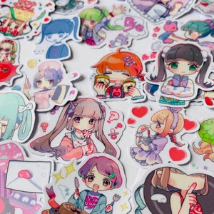 May include: A collection of colourful stickers featuring cartoon characters with different expressions and poses. The stickers are on a white background and include hearts, stars, and other decorative elements.