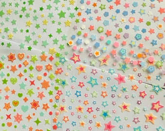 May include: Sheets of colorful star-shaped stickers in various sizes and designs. The stickers feature a range of colors including green, orange, pink, blue, and yellow. Some stars have patterns like polka dots and stripes, while others are solid.