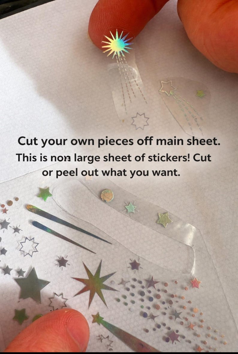 May include: Clear sticker sheet with various star and comet designs in iridescent colors. The text reads: "Cut your own pieces off main sheet. This is non large sheet of stickers! Cut or peel out what you want."