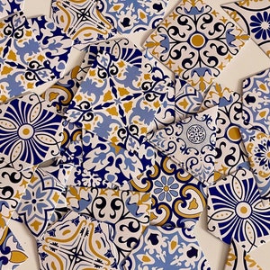 May include: A collection of blue and gold patterned ceramic tiles with intricate designs. The tiles are arranged in a random pattern, creating a visually appealing mosaic.