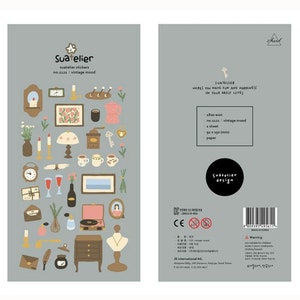 May include: A sheet of vintage-themed stickers featuring illustrations of a clock, candles, a lamp, a record player, a vase, a necklace, a key, a coffee pot, a teacup, a window, a book, a letter, and a flower. The stickers are on a light grey background. The text "Suatelier" and "no.1121: vintage mood" is printed on the sheet.