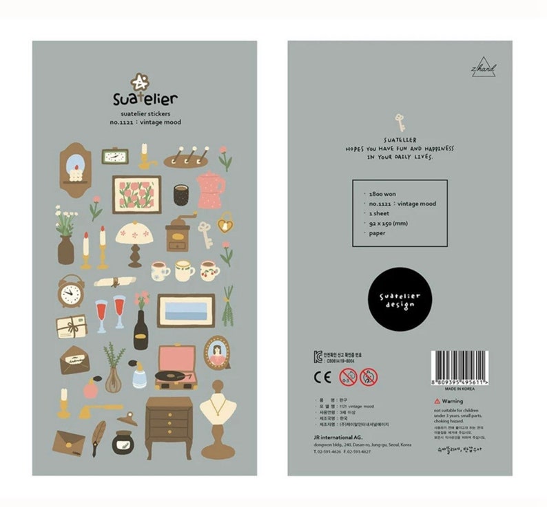 May include: A sheet of vintage-themed stickers featuring illustrations of a clock, candles, a lamp, a record player, a vase, a necklace, a key, a coffee pot, a teacup, a window, a book, a letter, and a flower. The stickers are on a light grey background. The text "Suatelier" and "no.1121: vintage mood" is printed on the sheet.