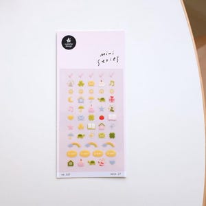 以下が含まれることがあります： 家、星、虹、ハートなど、さまざまなかわいいデザインが施されたカラフルなミニステッカーのシート。シートには「mini series」と「no. 127」と「deco. 27」の番号が印刷されています。