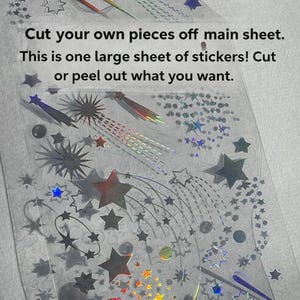 May include: A sheet of holographic stickers featuring star and comet designs in various sizes and colors. The text on the sheet reads, "Cut your own pieces off main sheet. This is one large sheet of stickers! Cut or peel out what you want."