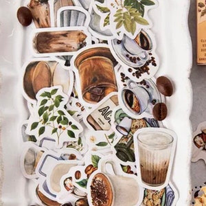May include: A collection of coffee-themed stickers featuring illustrations of coffee beans, coffee cups, coffee pots, and coffee plants. The stickers are on a white plate with a gold ribbon.
