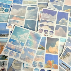 Puede incluir: Un conjunto de pegatinas con diseños de cielo y nubes en tonos azules, blancos y melocotón. Las pegatinas incluyen imágenes de nubes, arcoíris y una luna creciente. Algunas pegatinas tienen un diseño de cuadrícula.