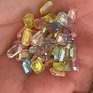 K&ouml;nnte beinhalten: Sortiment aus irisierenden, facettierten, rechteckigen Glasperlen in verschiedenen Gr&uuml;nt&ouml;nen, Gelb, Rosa und Lila.