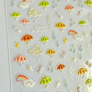 May include: Clear sticker sheet with colorful illustrations of rainbows, umbrellas, clouds, raindrops, and lightning bolts. The text "Rainbow Its rainy day" is also included. The stickers have a 3D effect.