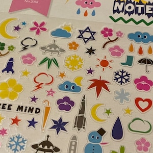 May include: A sheet of colorful stickers with various designs, including stars, clouds, hearts, snowflakes, rockets, and a snowman. The stickers are on a white background and have a glossy finish. The text "Space Note" is printed in black on a blue background at the top of the sheet.