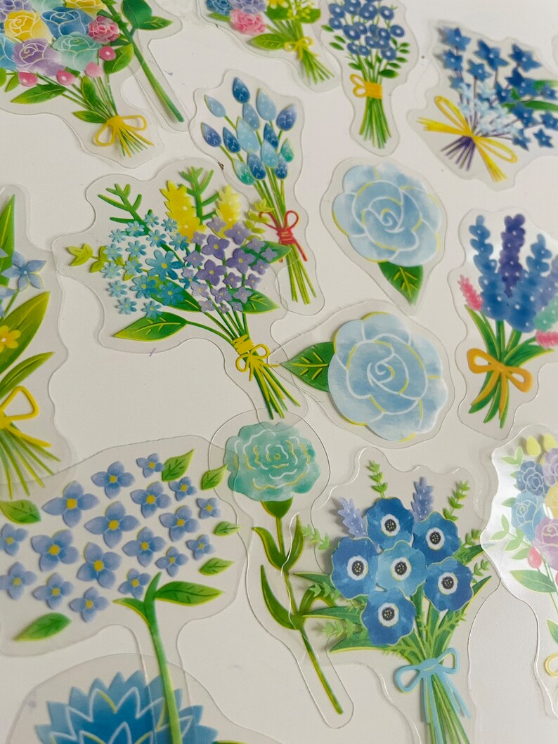 May include: A sheet of clear stickers featuring various blue and green floral bouquets. The bouquets are arranged in a random pattern on a white background.