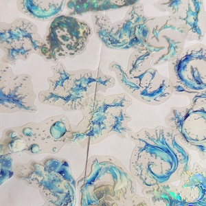 May include: A collection of individual stickers featuring various blue and white water splash designs. Each sticker has a translucent base and a holographic finish that reflects light, depicting dynamic waves, droplets, and swirling liquid patterns.
