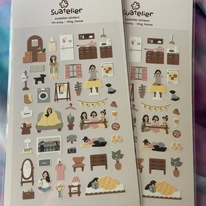 K&ouml;nnte beinhalten: Zwei Bl&auml;tter mit Aufklebern, die Illustrationen eines Hauses, von M&ouml;beln und Menschen zeigen. Die Aufkleber befinden sich auf einem hellgrauen Hintergrund und tragen den Text "Suatelier" und "no.1304 : vlog_home".