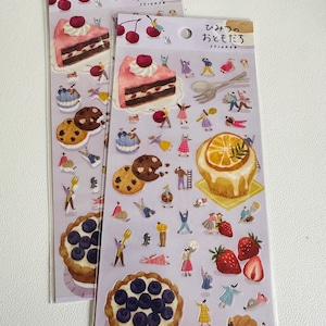May include: Two sheets of stickers featuring illustrations of cakes, pastries, fruit, and people. The stickers are on a purple background and have the Japanese text "ひっそり おやつ  sticker" which translates to "Quietly Snacks Sticker".