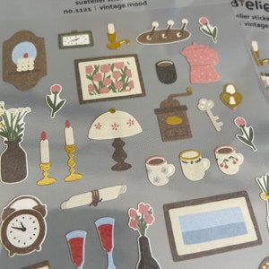 May include: A sheet of vintage-themed stickers featuring illustrations of a coffee grinder, candles, a lamp, a clock, a bottle of wine, a picture frame, a teapot, and other items. The stickers are labelled "Suatelier stickers no.1121: vintage mood".