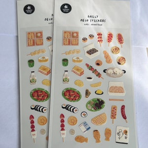 May include: A sheet of colourful stickers featuring various Korean street food items, including tteokbokki, kimbap, fish cakes, and more. The stickers are on a white background with the text "DAILY DECO STICKERS 1167: street food" printed at the top.