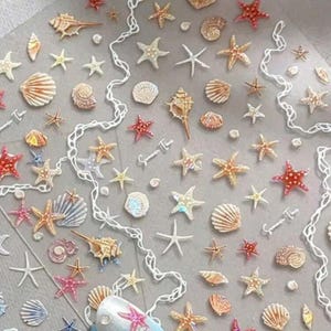May include: A collection of seashell and starfish stickers in various sizes and colors, including white, red, and tan. The stickers are arranged on a clear background with a white, wavy decorative element. Nail art with seashell and starfish designs is visible.
