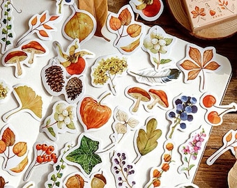May include: A sheet of autumn-themed stickers featuring various fall foliage, berries, mushrooms, and other nature-inspired designs. The stickers are printed on white paper and have a watercolor-like appearance.