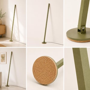 Puede incluir: L&aacute;mpara de pie verde oliva con un dise&ntilde;o minimalista. La l&aacute;mpara presenta un poste delgado y rectangular que se inclina ligeramente, sujeto a una base redonda con fondo de corcho. Un cable de alimentaci&oacute;n negro se extiende desde la base. La l&aacute;mpara se muestra en un sal&oacute;n moderno.
