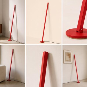 Puede incluir: Una l&aacute;mpara de pie roja y alta con un dise&ntilde;o minimalista. La l&aacute;mpara tiene un poste delgado y rectangular que se apoya en una pared, con una base circular. La l&aacute;mpara es de metal y tiene un acabado mate. La l&aacute;mpara mide aproximadamente 178 cm de altura.