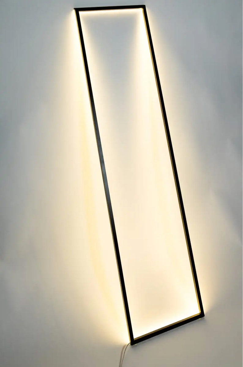 Side view of leaning floor lamp with warm ambient light in cozy modern corner. Geometric frame adds a sculptural element to any interior