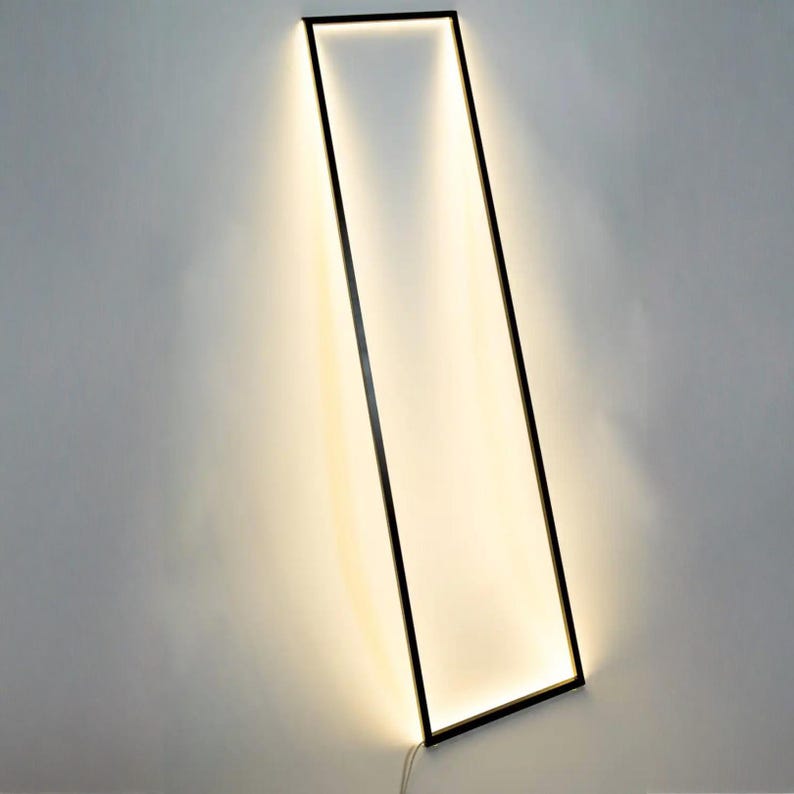 Side view of leaning floor lamp with warm ambient light in cozy modern corner. Geometric frame adds a sculptural element to any interior.