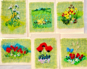 May include: Set of six handmade cards featuring embroidered floral designs. Each card has a different floral motif, including white and yellow flowers, red poppies, and a blue butterfly.