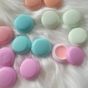 May include: Assortment of pastel colored macaron shaped containers with a single pink lip balm container in the center.