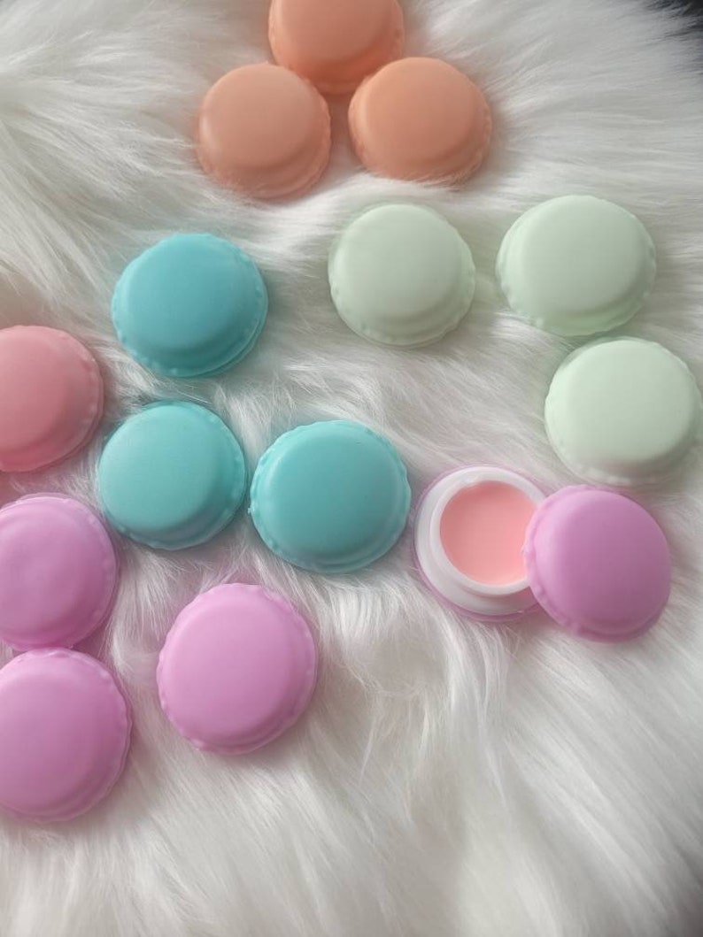 May include: Assortment of pastel colored macaron shaped containers with a single pink lip balm container in the center.