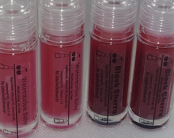 May include: Four clear lip gloss tubes containing pink, red, and burgundy coloured gloss. The tubes are labelled "Watermelon Baby" and "Black Cherry" with the brand name "by IzzabelleBeauty".