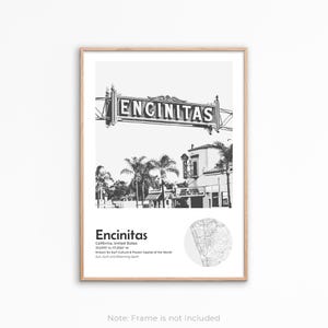 May include: Monochrome framed print of Encinitas, California, with a sign bearing the city's name. The print includes coordinates and a map. Palm trees and buildings are in the background.