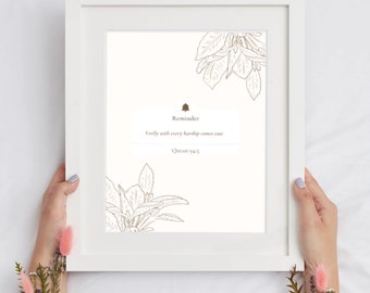 May include: A white framed print with a brown floral design and the text "Reminder: Verily with every hardship comes ease. Quran 94:5".