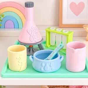 May include: A toy science set on a mint green tray featuring a pink flask with an atom symbol, a lime green test tube rack with three tubes, a yellow cup, a light blue cauldron with raindrop details, and a matching light blue stirring spoon.