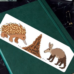 May include: A sticker featuring a brown and yellow echidna, a brown ant hill, and a brown aardvark. The animals are cartoon-style illustrations.