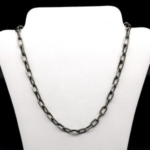 May include: A silver chain necklace with a twisted rope design. The chain is made of oval links.