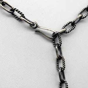 May include: A silver chain necklace with a twisted rope design and a lobster clasp closure.