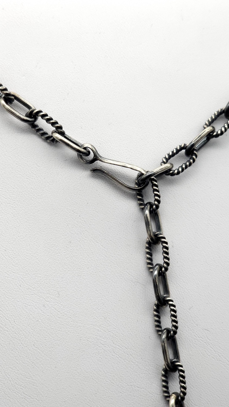 May include: A silver chain necklace with a twisted rope design and a lobster clasp closure.
