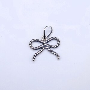 This bow pendant measures 1 inch wide & 3/4 inches tall
The bail will fit a strand of 6mm Navajo Pearls