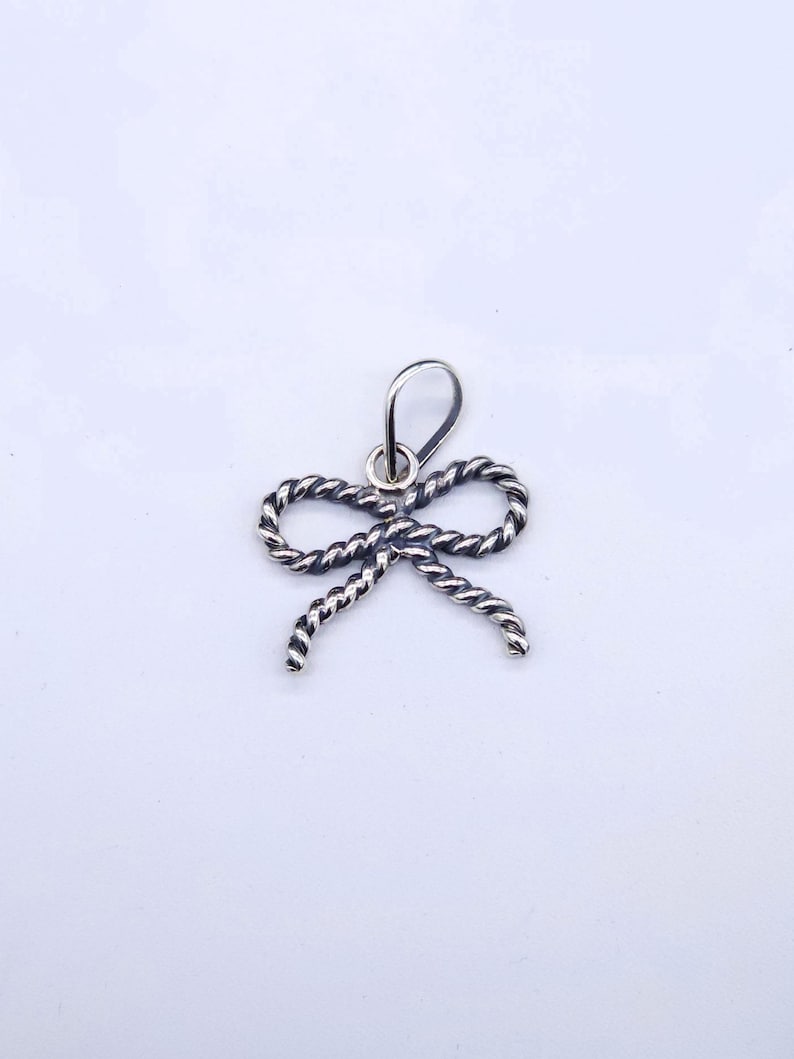 This bow pendant measures 1 inch wide & 3/4 inches tall
The bail will fit a strand of 6mm Navajo Pearls
