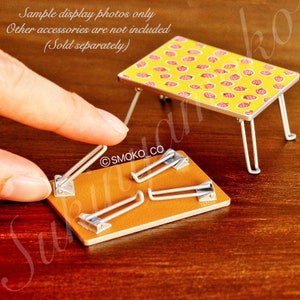 May include: A yellow folding table with a strawberry pattern. The table is made of metal and has a brown leather-like top. The table is folded up and the legs are visible. The table is on a wooden surface.