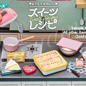 Könnte beinhalten: Ein Miniatur-Küchenspielset mit einem rosa Handmixer, einem rosa Topf, einem Timer, einer Schachtel Süßigkeiten und einem Messbecher. Das Set ist Teil der Re-Ment Sweets Recipes-Serie.