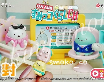 May include: A set of Sumikko Gurashi character figurines, including a penguin wearing a pink scarf and sunglasses, a green turtle wearing a blue kimono, a blue cat wearing a blue suit, and a yellow chick wearing a yellow hat. The figurines are sitting on chairs and a seesaw. The set also includes a blue and white television screen with a news report, a blue camera, and a microphone. The set is part of the Sumikko Gurashi CH collection.