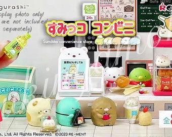Op de afbeelding: Een miniatuur Sumikko Gurashi-winkelset met verschillende personages en items, waaronder een automaat, een ijsvriezer, een frituurkraam en een drankkoeler. De set is gemaakt van plastic en heeft felle kleuren en gedetailleerde ontwerpen. De tekst op het bord luidt "Sumikko Convenience Store" en "Sumikko Gurashi".