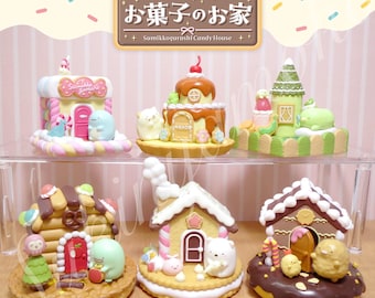 Op de afbeelding: Een set van zes miniatuur Sumikkogurashi Candy Houses, elk met een ander ontwerp en personage. De huizen zijn gemaakt van kleurrijk snoep en versierd met sprankelende suikers en andere zoete lekkernijen. De huizen worden getoond op een helder rek met een witte achtergrond.