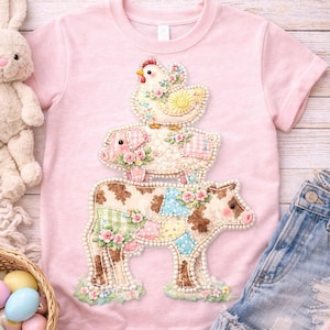 May include: Pink t-shirt featuring a stacked farm animal design. The design includes a cow, pig, and chicken, each adorned with floral and patchwork details. The shirt is paired with denim shorts and pink sneakers, suggesting a children's clothing theme.