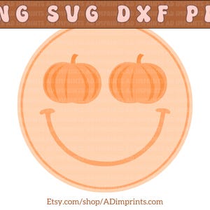 Op de afbeelding: Een perzikkleurig smiley-gezicht met twee oranje pompoenen als ogen. Het smiley-gezicht is omrand met een donkerdere oranje kleur.