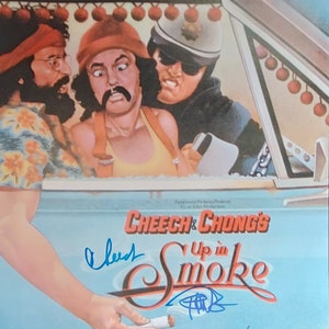 Pode incluir: Um cartaz de filme para o filme "Cheech & Chong's Up in Smoke". O cartaz apresenta um fundo azul com o título do filme em letras brancas. O cartaz também apresenta uma foto de Cheech Marin e Tommy Chong, junto com um oficial de polícia, em um carro. O cartaz é assinado por Cheech e Chong.