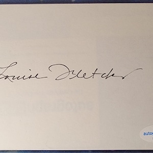 May include: An autographed card featuring the signature of Louise Fletcher in black ink. The signature is centered on a cream-colored card. A small, circular sticker with the text "autograph coa" and the serial number SC78625 is in the bottom right corner.