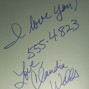 May include: Blue ink signature on a white background that reads "I love you! 555-4823 Love Candia Walls".